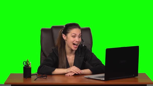 Femme d'affaires dans les écouteurs parlant par webcam et regarder ordinateur portable avec des émotions de joie. Écran vert. Mouvement lent — Video