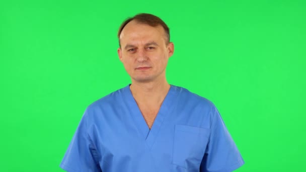 Medische man flirt en knipoogt terwijl hij naar de camera kijkt. Groen scherm — Stockvideo