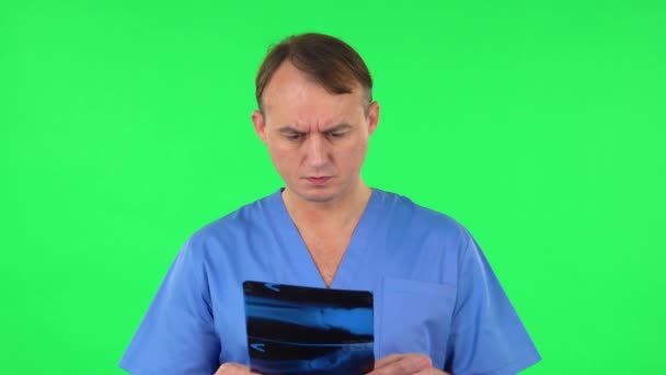 Male doctor in blue coat reviewing x-ray pointing on snapshot. Green screen — Stock Video