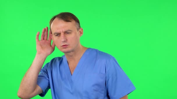 Uomo medico che si tiene per mano vicino all'orecchio cercando di ascoltare notizie interessanti che esprimono concetto di comunicazione. Schermo verde — Video Stock