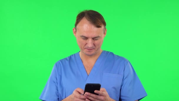 El médico mandándole mensajes telefónicos y regocijándose. Pantalla verde — Vídeos de Stock