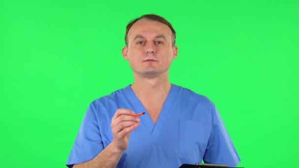 Medikal adam siyah klasördeki kağıtları kalemle dolduruyor. Yeşil Ekran — Stok video
