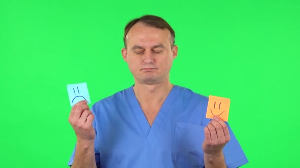 L'homme médical tenant le bâton de papier exprimant l'humeur horrible prend alors un autre exprimant la bonne humeur. Écran vert — Video