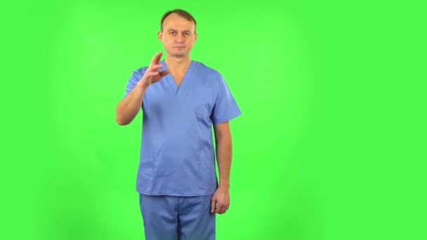 Медик махає рукою і показує жест сюди. Зелений екран — стокове відео