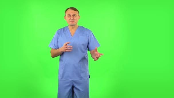 Medical man emotionally looks at something, comments and then disappointedly gives up hands. Green screen — Stock Video