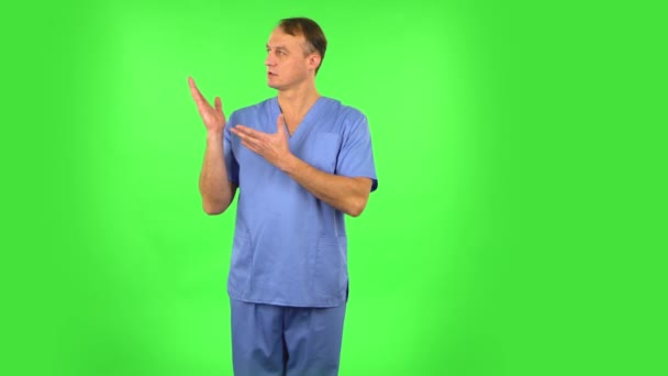 Medische man praat en wijst zijhand voor iets, kopieer ruimte. Groen scherm — Stockvideo
