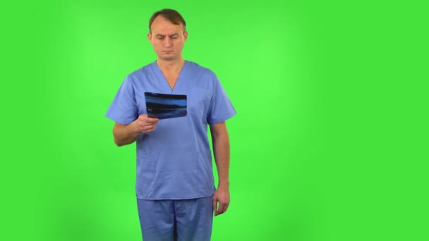 Male doctor in blue coat reviewing x-ray pointing on snapshot. Green screen — Stock Video