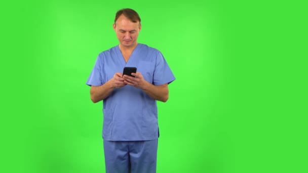 Medisinsk mann tekster på telefonen og gleder seg. Grønn skjerm – stockvideo