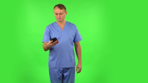 El hombre médico hace selfie en el teléfono móvil y luego busca fotos en la pantalla verde . — Vídeo de stock