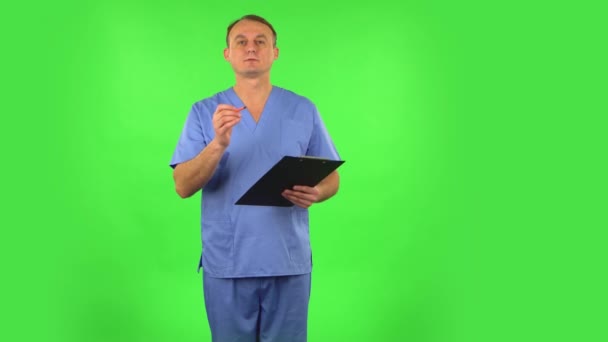 Ιατρικός άνθρωπος σκέφτεται, μιλάει και γράφει σε μαύρο φάκελο με pensil. Πράσινη οθόνη — Αρχείο Βίντεο