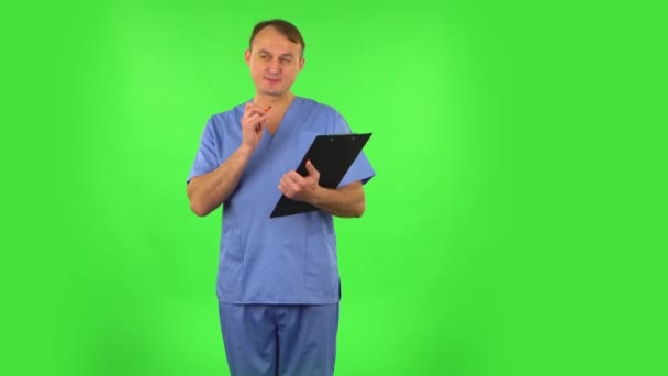 Medical man thinks, speaks and writes at black folder with pensil. Green screen — 비디오