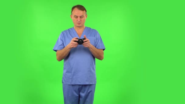 Medical man playing a video game using wireless controller and rejoicing in victory. Green screen — 비디오