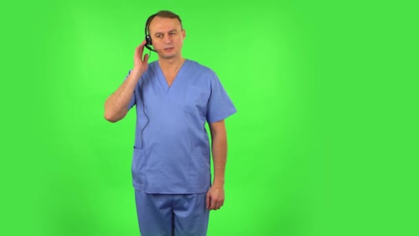 Medical man talking on headphones at support service. Green screen — Stock Video