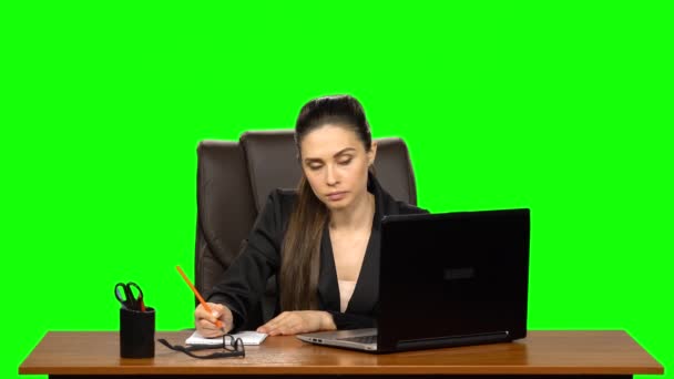 A női menedzser egy laptopon dolgozik és jegyzetel. Zöld képernyős háttér — Stock videók
