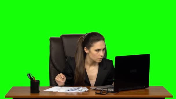 ノートパソコンで働く少女は、突然、テーブルの上の文書を探し始め、見つけると幸せ。緑の画面 — ストック動画