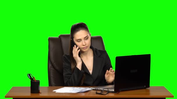 Жінка, яка працює на ноутбуці, відповідає на дзвінок мобільним телефоном, сумує і дуже щаслива. Зелений екран — стокове відео