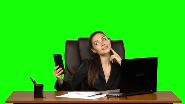 Femme d'affaires sur le lieu de travail prend un selfie sur son téléphone portable puis regarde joyeusement la photo. Écran vert. Studio — Video