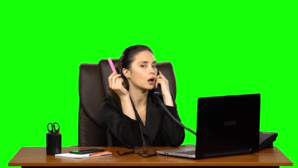 Děvče na pracovišti pracuje na laptopu, mluví na dvou telefonech a piluje hřebíky. Zelená obrazovka — Stock video