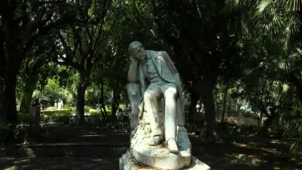 КАТАНИЯ, СИЦИЛИ, ИТАЛИЯ - СЭПТ, 2019: Скульптура человека, сидящего на камне в зеленом парке и мыслящего — стоковое видео