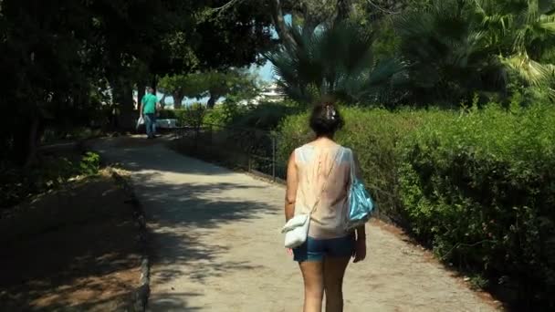 CATÂNIA, SICILIA, ITÁLIA - SEPT, 2019: Jovem mulher caminhando pela estrada, cercada por árvores verdes e arbustos — Vídeo de Stock