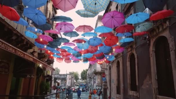 意大利西西里卡塔尼亚- 2019年9月：五颜六色的雨伞挂在餐馆和咖啡馆之间的街道上 — 图库视频影像