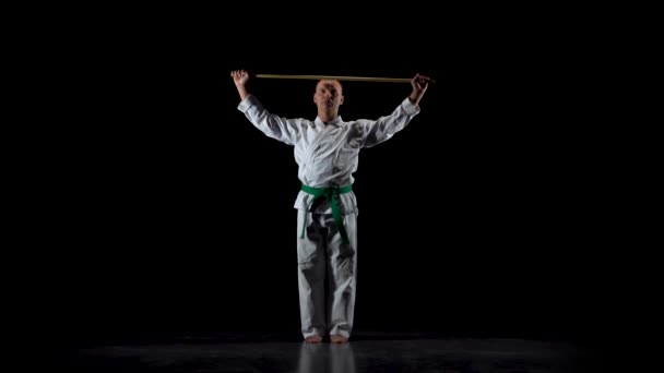 Kendo combattente su kimono bianco praticare arte marziale con il bokken di bambù su sfondo nero. Rallentatore — Video Stock