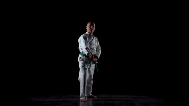 Kendo lutador no quimono branco praticando arte marcial com o bokken de bambu no fundo preto. Movimento lento — Vídeo de Stock