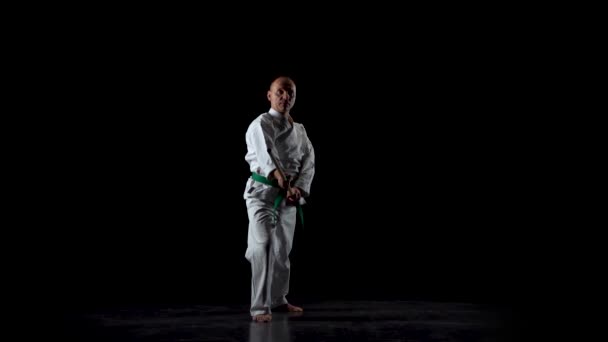Kendo-Kämpfer auf weißem Kimono, der Kampfkunst mit dem Bambusbokken auf schwarzem Hintergrund praktiziert. Zeitlupe — Stockvideo
