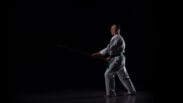 Combattant kendo sur kimono blanc pratiquant l'art martial avec le bokken en bambou sur fond noir. Mouvement lent — Video