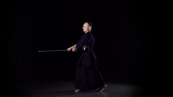 Guerrero Kendo practicando arte marcial con la espada Katana sobre fondo negro. Movimiento lento — Vídeos de Stock