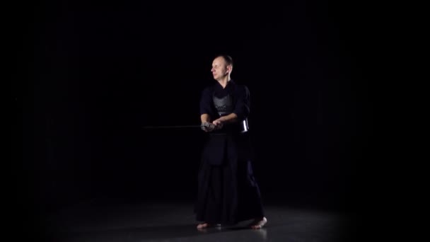 Guerrero Kendo practicando arte marcial con la espada Katana sobre fondo negro. Movimiento lento — Vídeo de stock