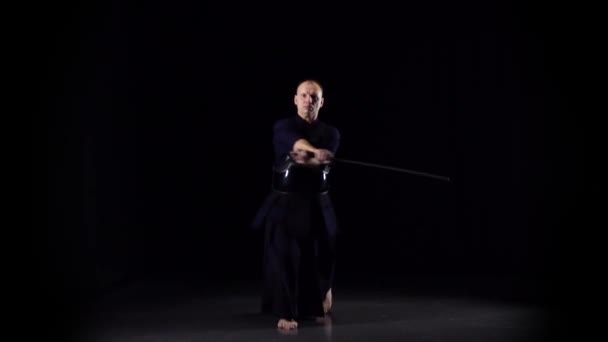 Guerrero Kendo practicando arte marcial con la espada Katana sobre fondo negro. Movimiento lento — Vídeo de stock