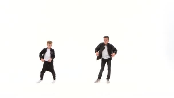 Los niños pequeños están bailando una danza moderna sobre el fondo blanco en chaquetas de cuero negro y jeans — Vídeo de stock