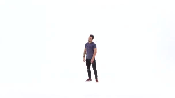 El hombre está bailando breakdance sobre el fondo blanco en camiseta gris simple y jeans grises — Vídeo de stock