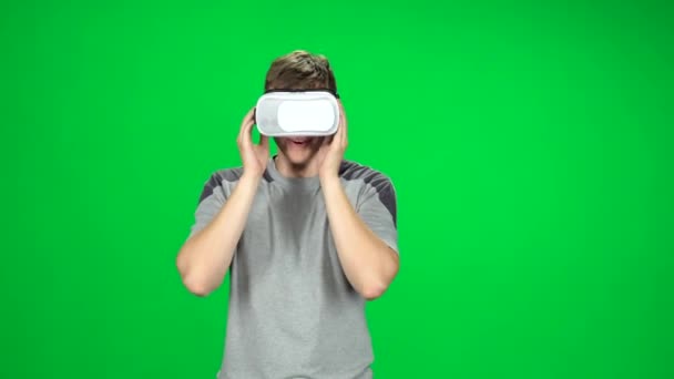Χαμογελώντας άνθρωπος φορώντας μια εικονική πραγματικότητα ακουστικά πηγαίνει στην πράσινη οθόνη — Αρχείο Βίντεο