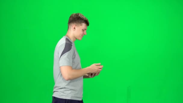 Man gaat en neemt een selfie met smartphone op groen scherm in de studio. Zijaanzicht — Stockvideo