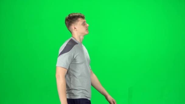 Mladý muž kráčí po zelené obrazovce, Chroma Key. Boční pohled — Stock video