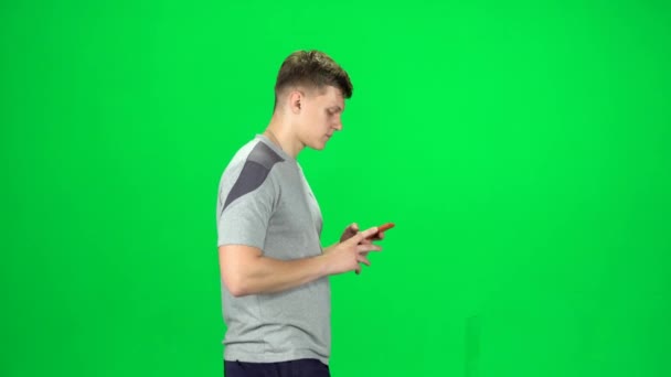Hombre va y se toma una selfie con teléfono inteligente en la pantalla verde en el estudio. Vista lateral — Vídeos de Stock