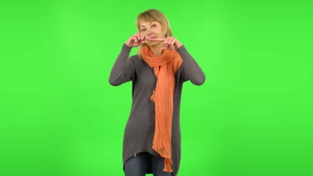 Middle aged blonde woman is smiling and showing heart with fingers then blowing kiss. Green screen — 비디오