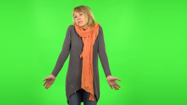 Een blonde vrouw van middelbare leeftijd haalt haar schouders op en zucht. Groen scherm — Stockvideo