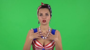 Portrait of beautiful girl in a swimsuit is talking about something then making a hush gesture, secret. Green screen