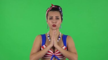 Portrait of beautiful girl in a swimsuit is standing worrying in expectation then smiles with relief, carried. Green screen