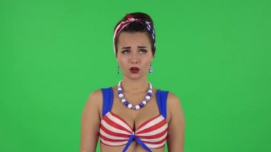 Portrait of beautiful girl in a swimsuit in anticipation of worries, then guilty hides her eyes. Green screen