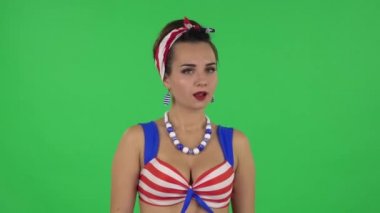 Portrait of beautiful girl in a swimsuit is upset, waving her hands in indignation. Green screen