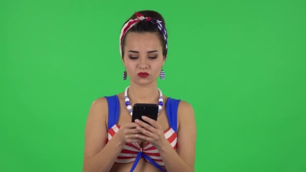 Portret pięknej dziewczyny w stroju kąpielowym gniewnie pisze na telefonie. Zielony ekran — Wideo stockowe