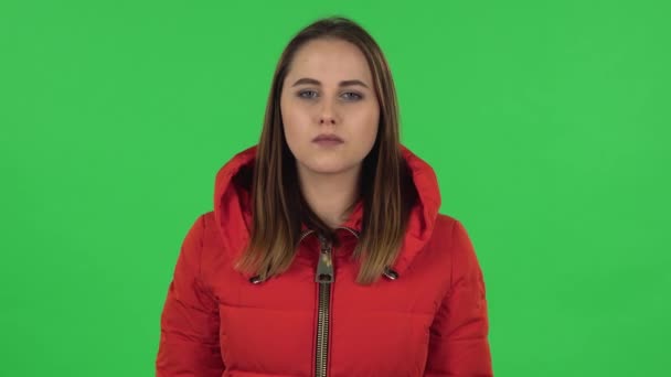 El retrato de una chica encantadora con una chaqueta roja abajo aplaude con insatisfacción. Pantalla verde — Vídeo de stock