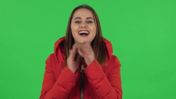 A piros kabátos csinos lány portréja megtapsolja a kezét a boldog örömtől és gyönyörtől. Zöld képernyő — Stock videók