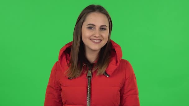 Retrato de una chica encantadora en una chaqueta roja abajo es coqueta mano saludando y mostrando gesto ven aquí. Pantalla verde — Vídeos de Stock