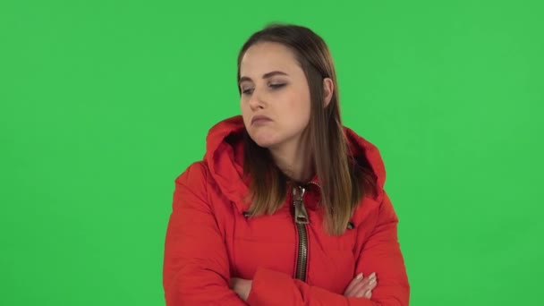 Portret van een mooi meisje in een rood donsjas is erg beledigd en wegkijkend. Groen scherm — Stockvideo
