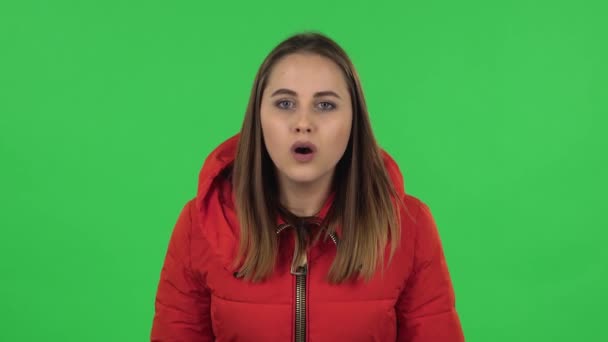 Retrato de chica encantadora en una chaqueta roja está mirando a la cámara con anticipación, a continuación, muy molesto. Pantalla verde — Vídeo de stock